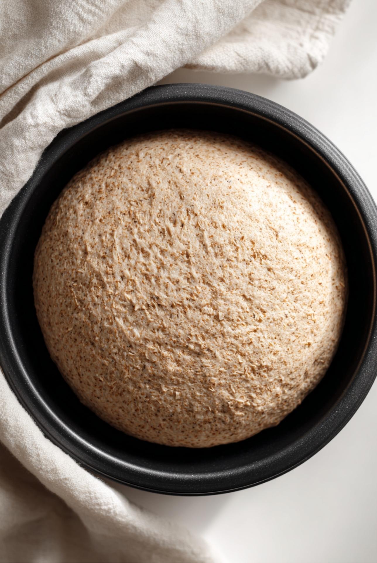 Bowl of high fiber bread dough rising, made with whole wheat flour and ground flaxseed.