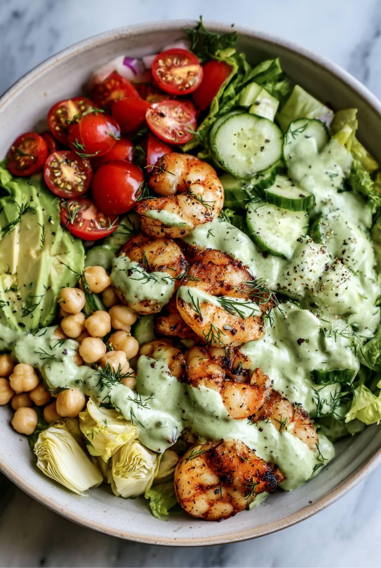 Bowl of shrimp salad with chickpeas, cucumbers, avocado, and avocado dressing for a high-fiber lunch.