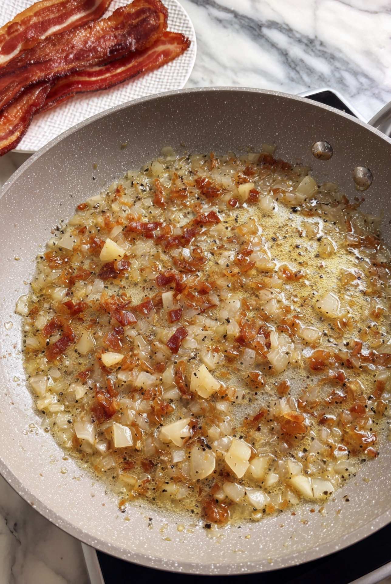 Skillet with caramelized onions and bacon fat for German potato salad dressing.