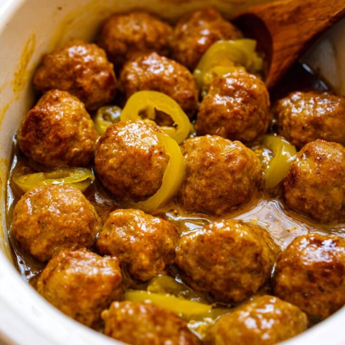 Overhead crockpot shot with wooden spoon stirring Mississippi meatballs.