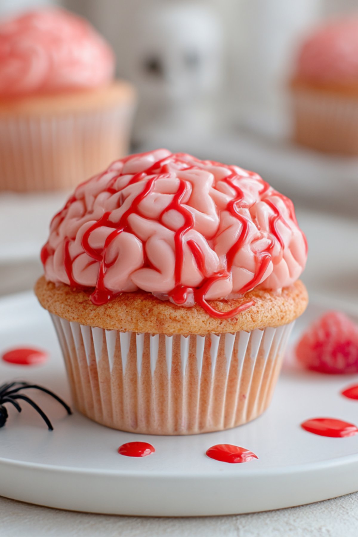 Close-up of a zombie brain cupcake topped with pink strawberry frosting in a brain pattern and red syrup drizzle.