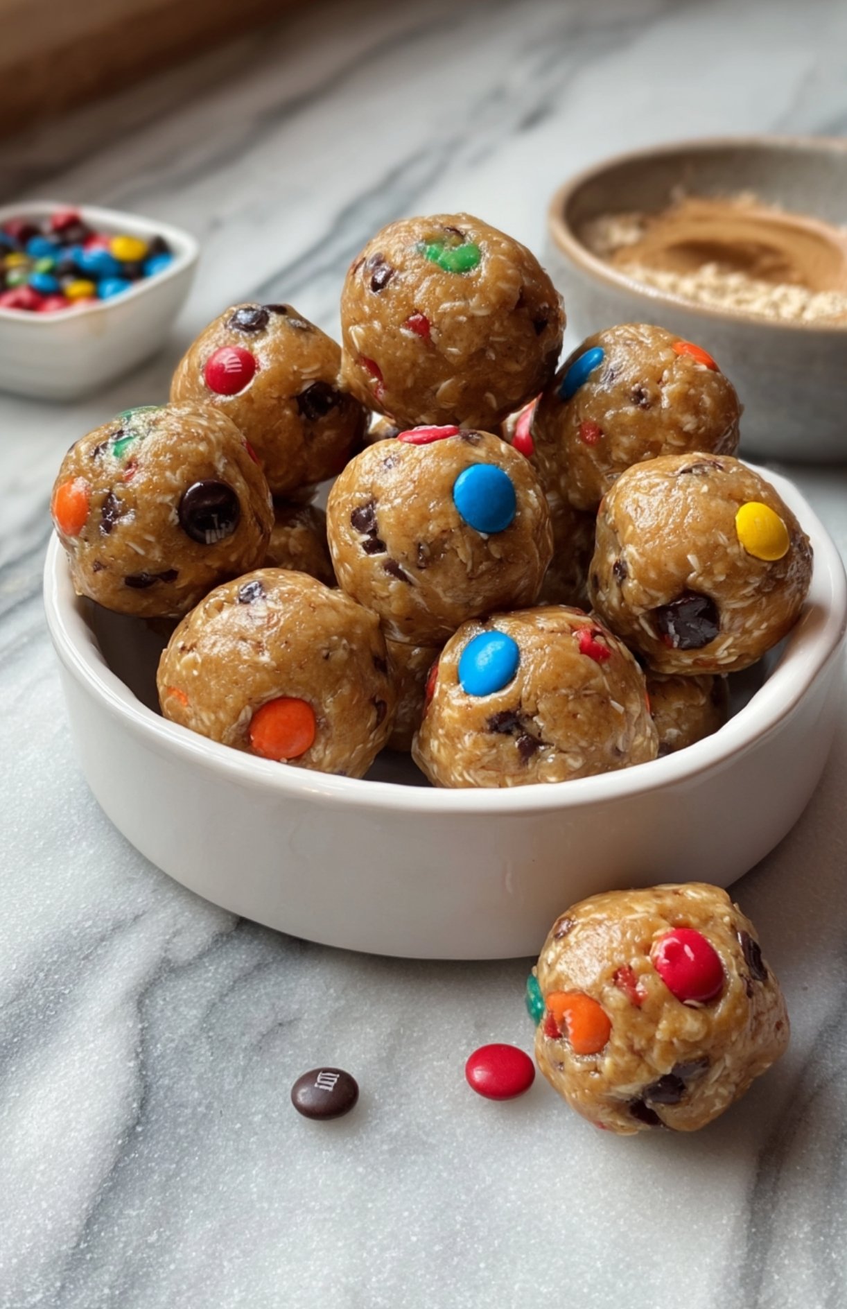 Close-up of peanut butter oat protein energy balls with colorful M&Ms in a white bowl.