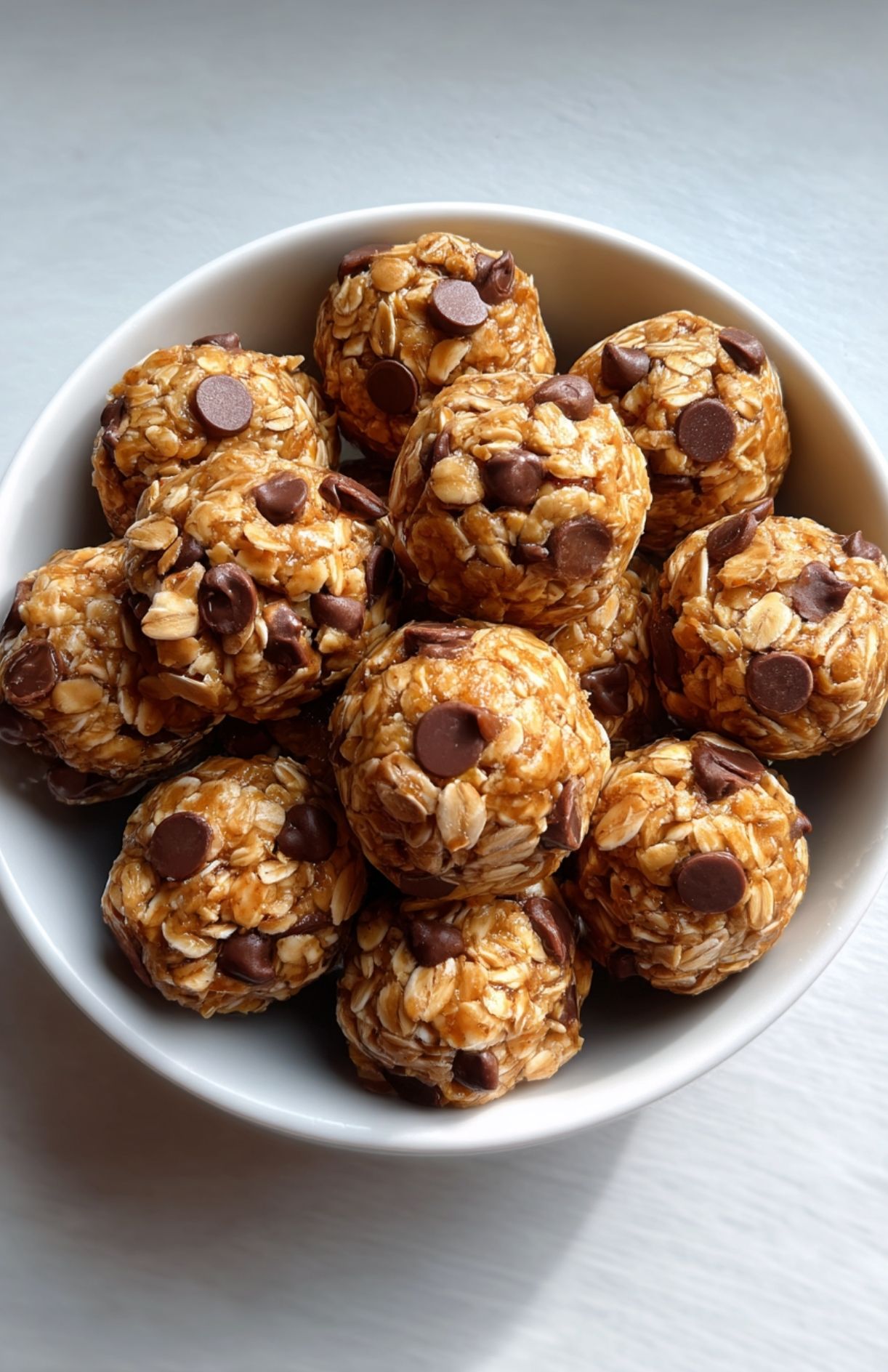 White bowl filled with no bake protein energy balls made with oats and mini chocolate chips.