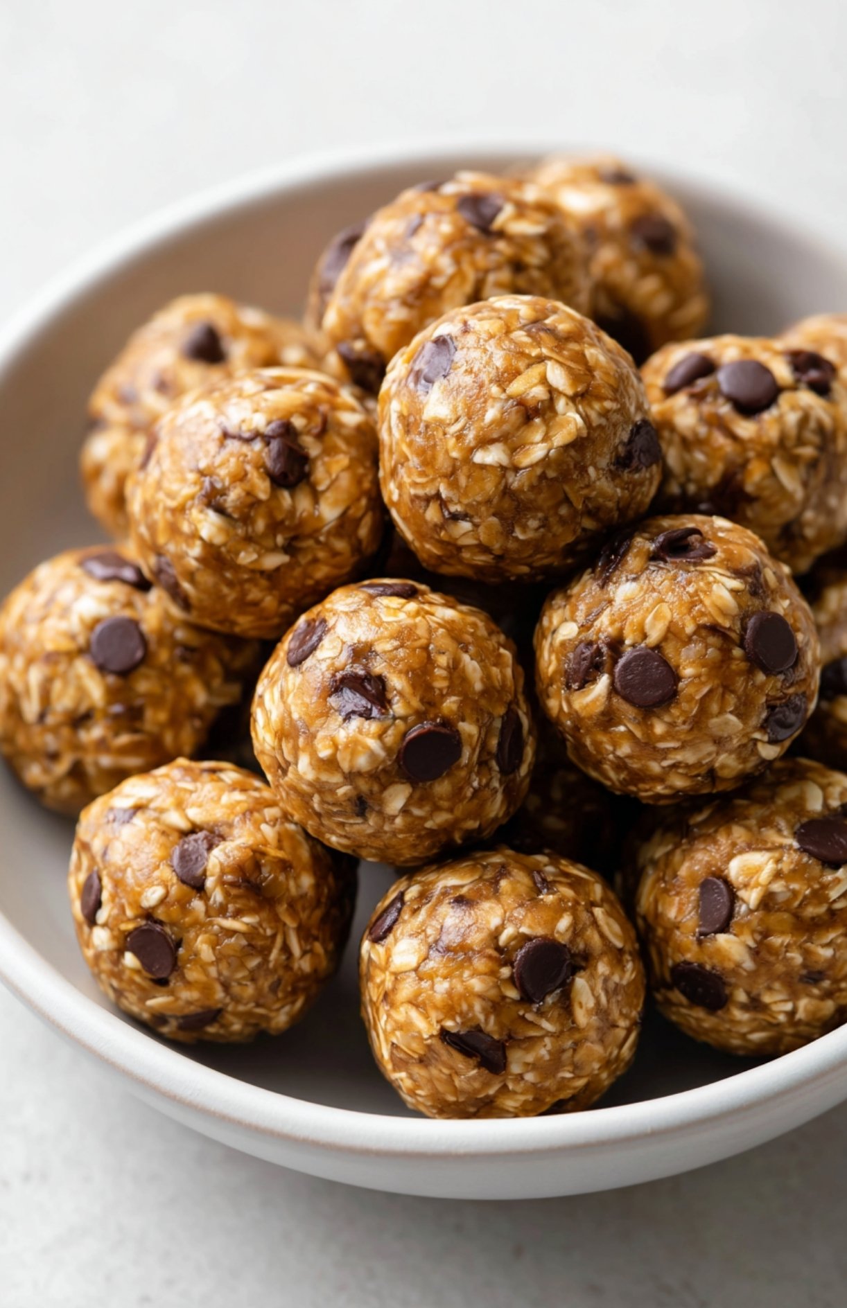 Overhead bowl filled with several no bake protein balls made with oats and chocolate chips.