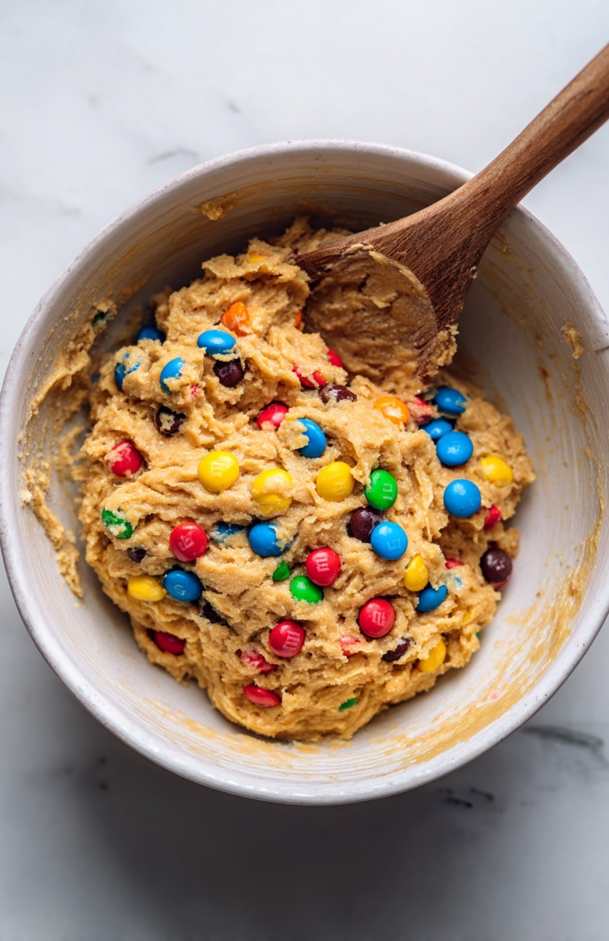 Mixing bowl with peanut butter protein energy ball dough and colorful M&Ms.