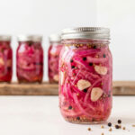 Graphic pin showing two views of bright pink pickled red onions in glass jars with text overlay reading Pickled Red Onion Recipe No Sugar