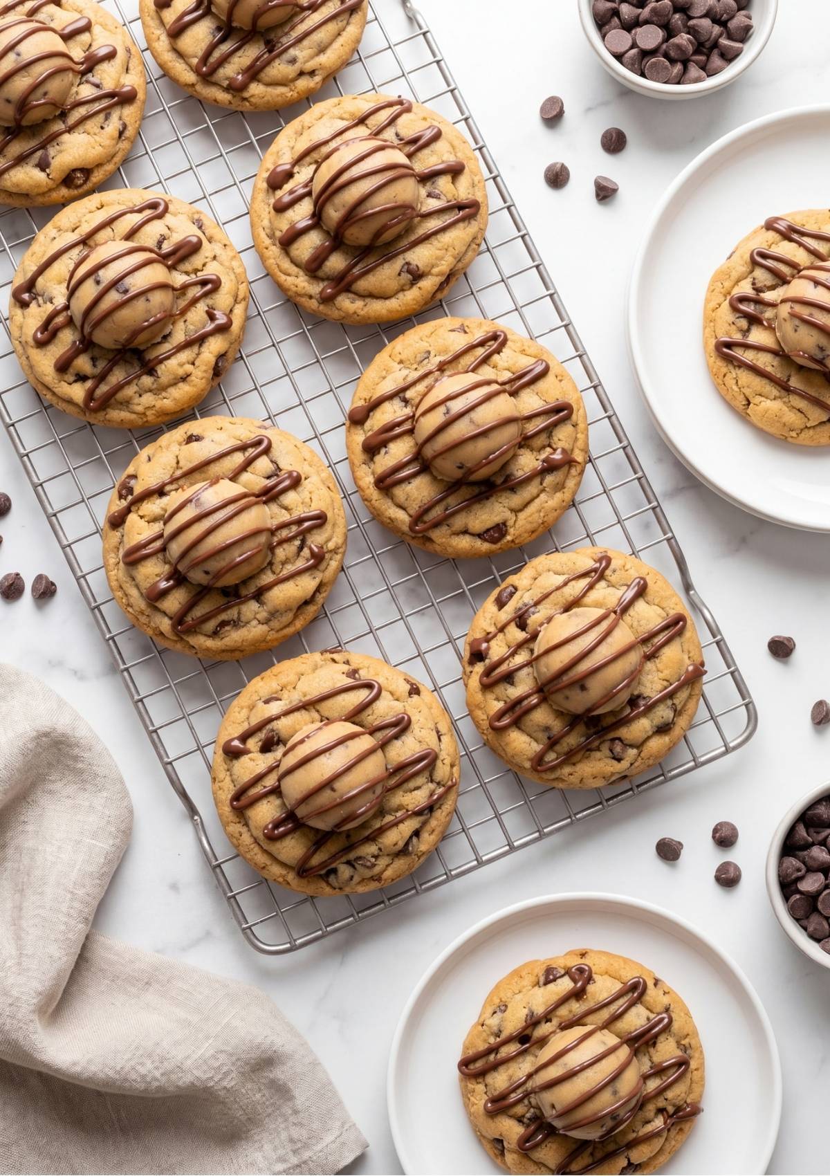 Overhead view of soft baked chocolate chip cookies topped with edible dough balls and chocolate drizzle sitting on a wire cooling rack