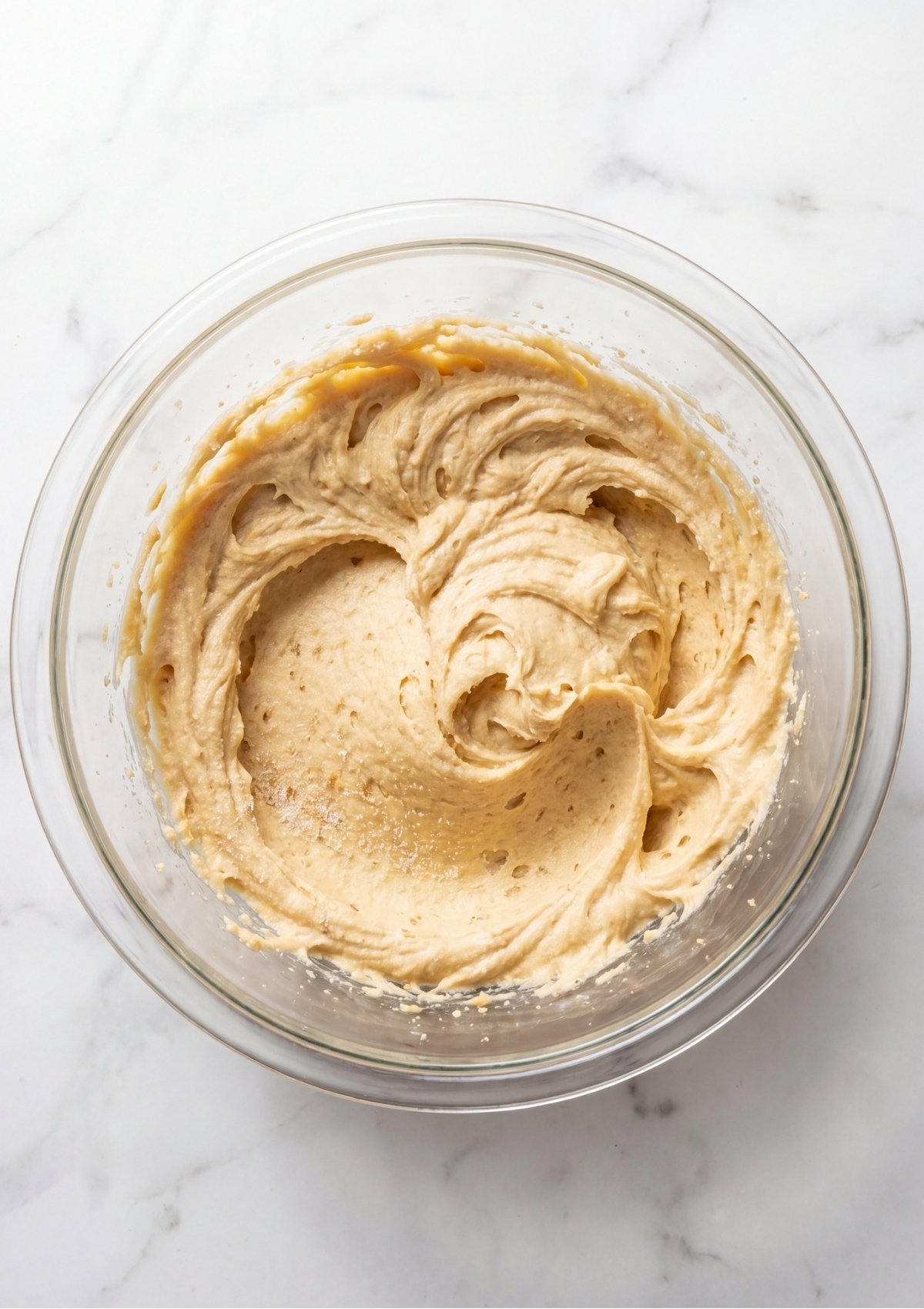 A glass mixing bowl containing creamed butter and sugar mixture for a cookie dough cookies recipe