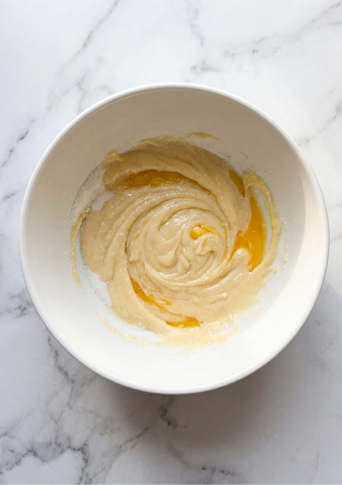 Thick choux pastry dough being combined in a white bowl for a homemade patriotic dessert recipe.